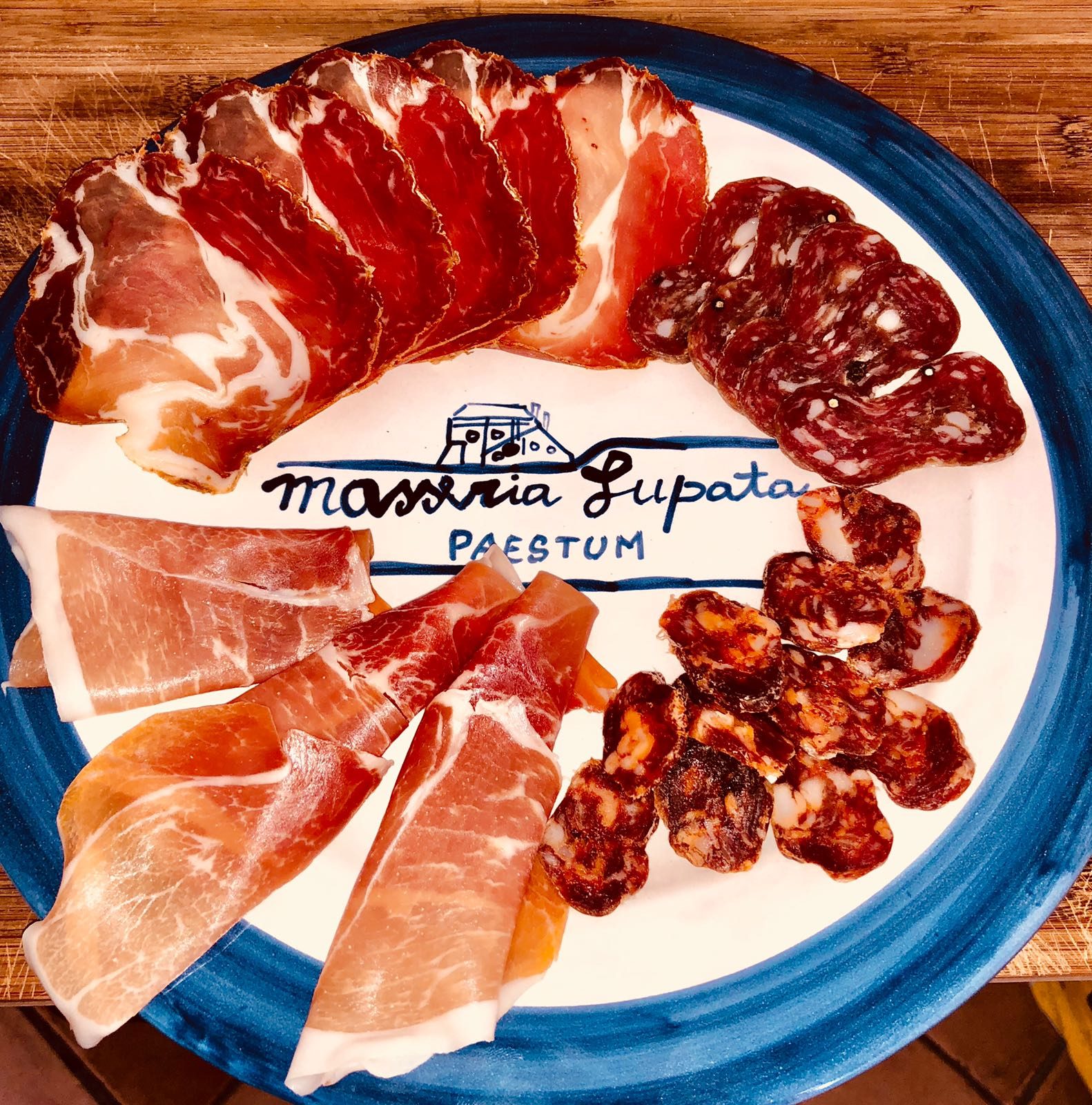 Tagliere di salumi su un piatto in ceramica con il logo della masseria
